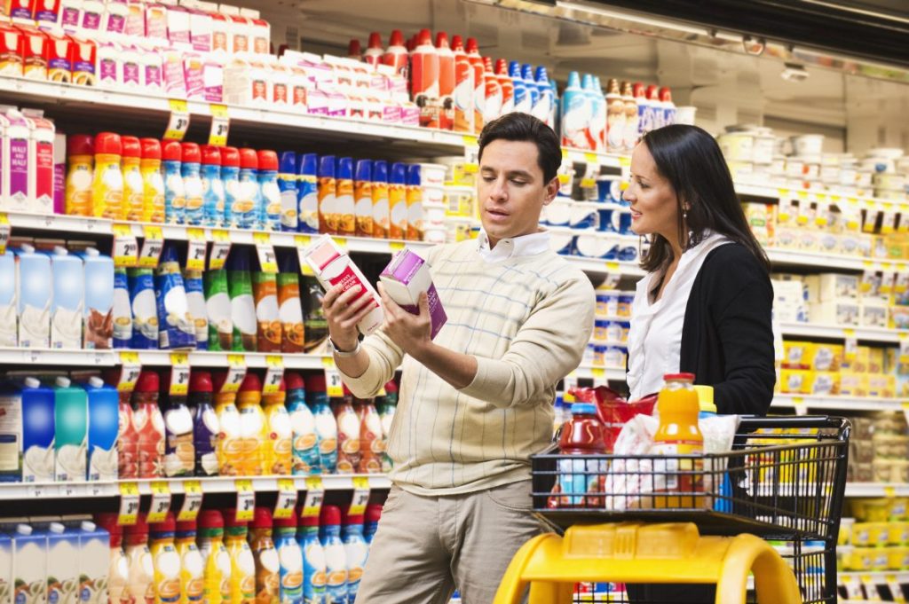 A husband and wife compare price pack architecture during a grocery store run.