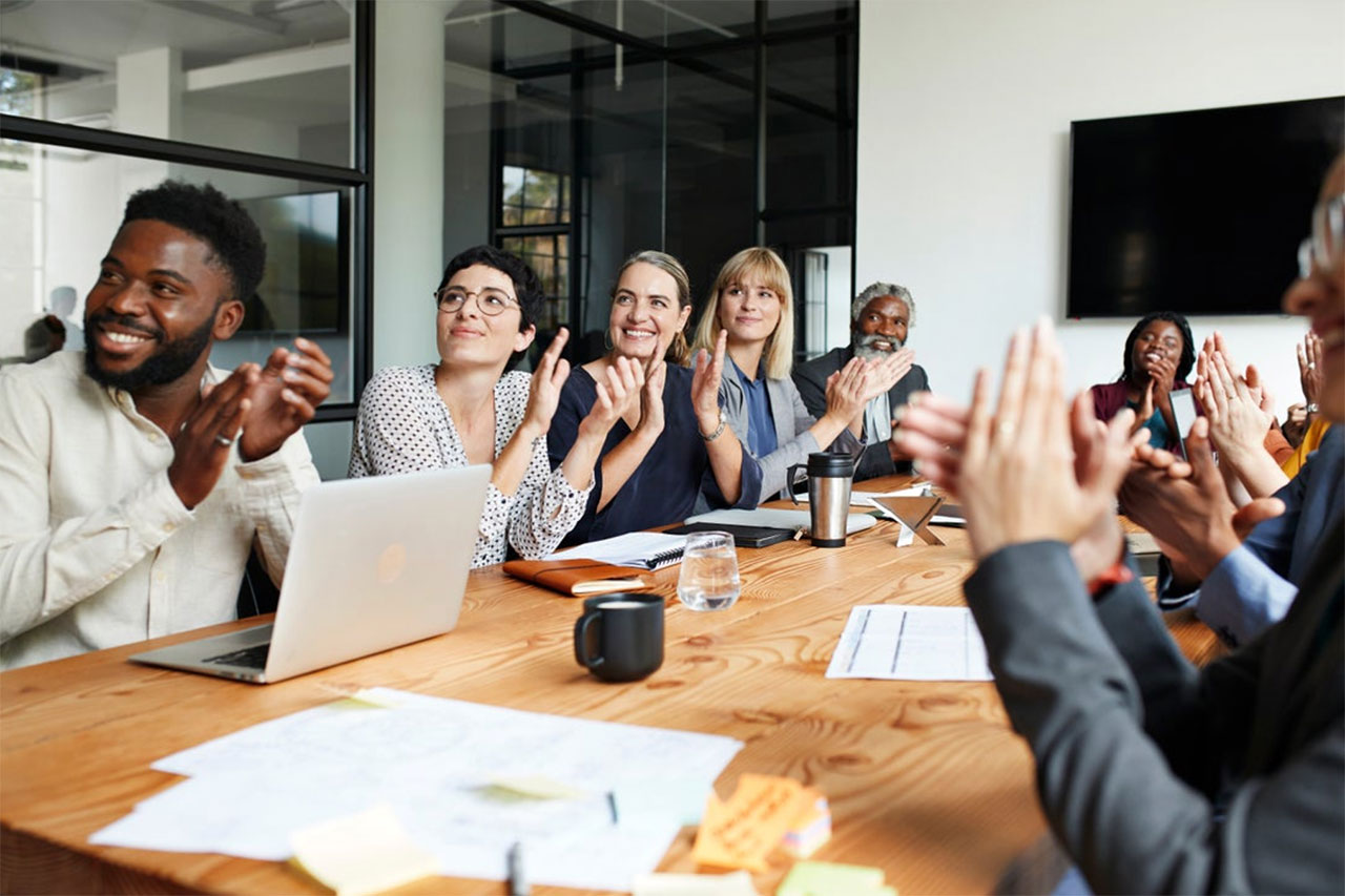 A group of people in a meeting clapping