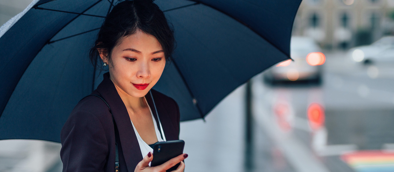Young Business Woman Using Smart Phone In The Rain