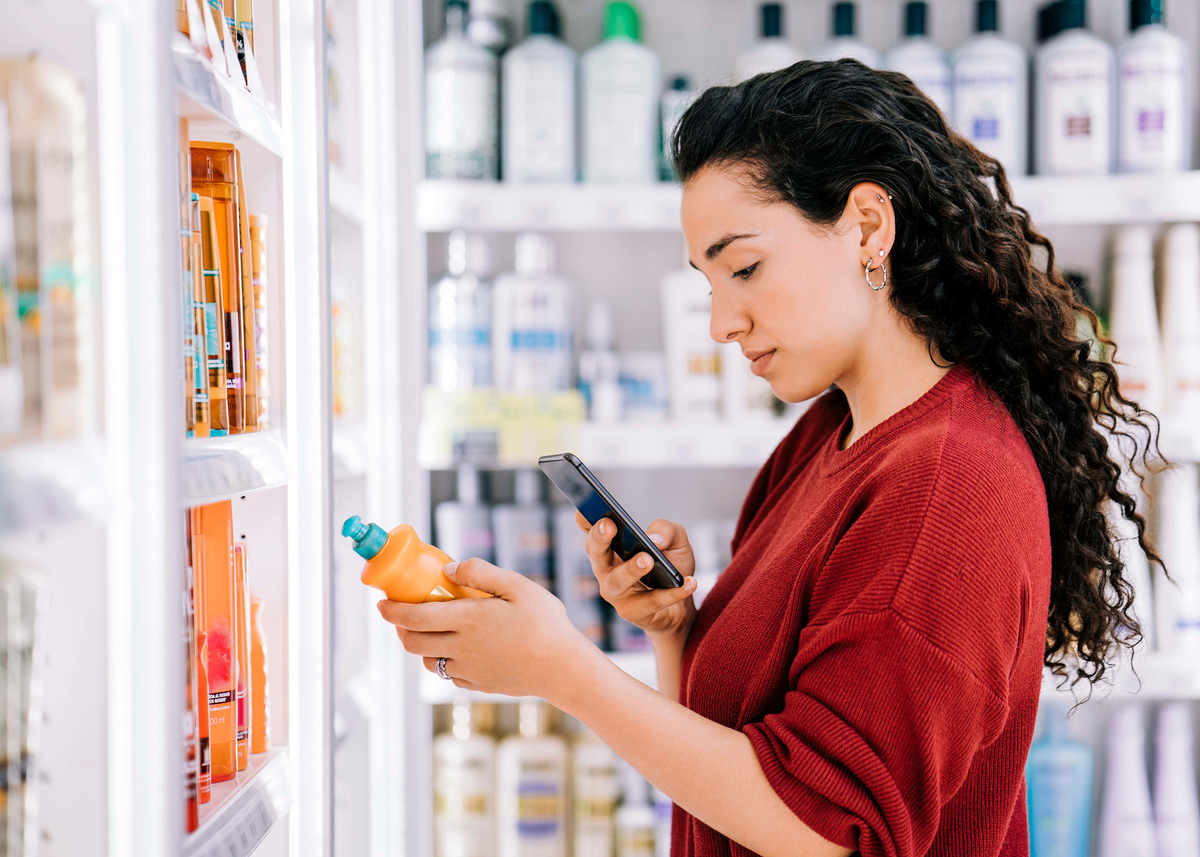 Woman in red shirt scanning a bar code in the beauty aisle