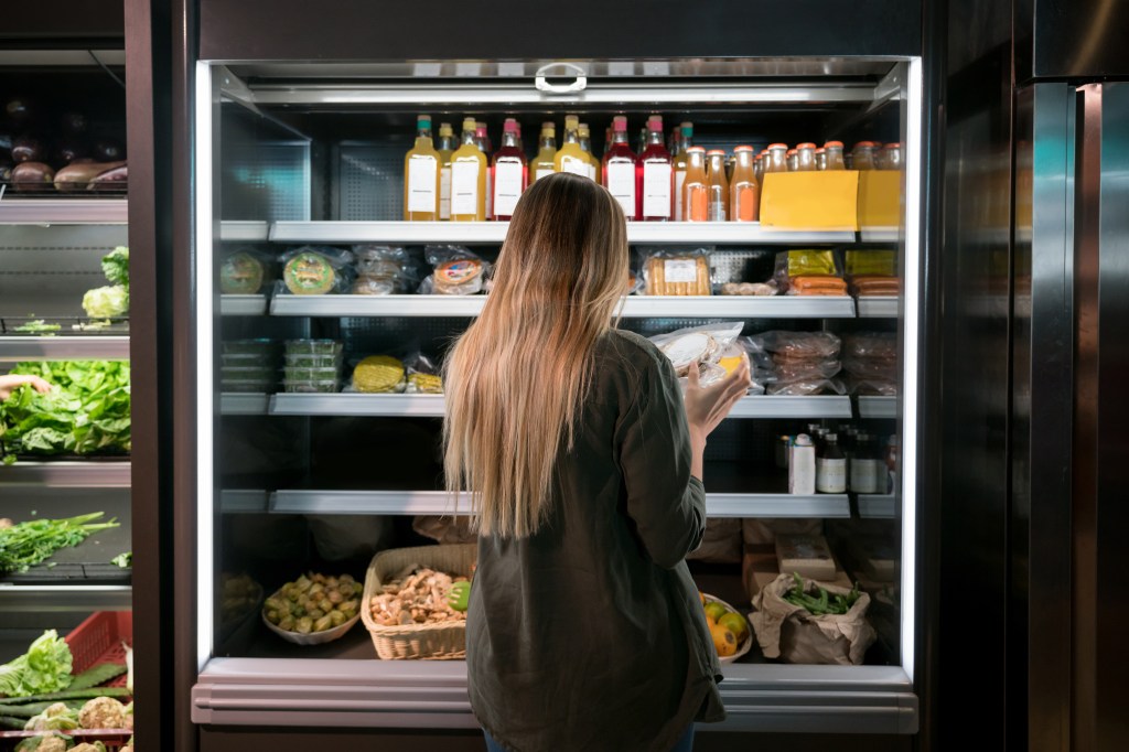 a woman considering the price of a grocery item impacted by inflation