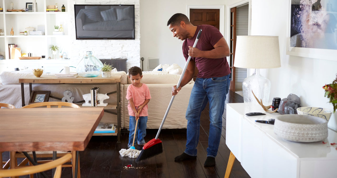 Man sweeping with help from his son