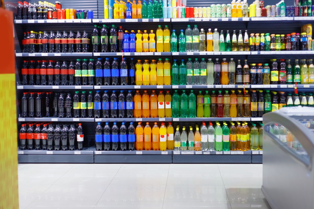 A row of various beverages in a supermarket.