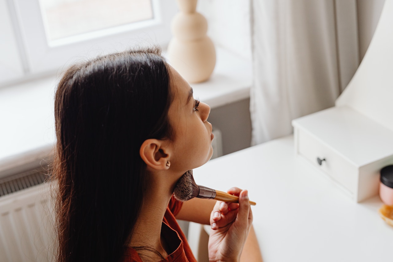 A young Hispanic woman applies beauty products