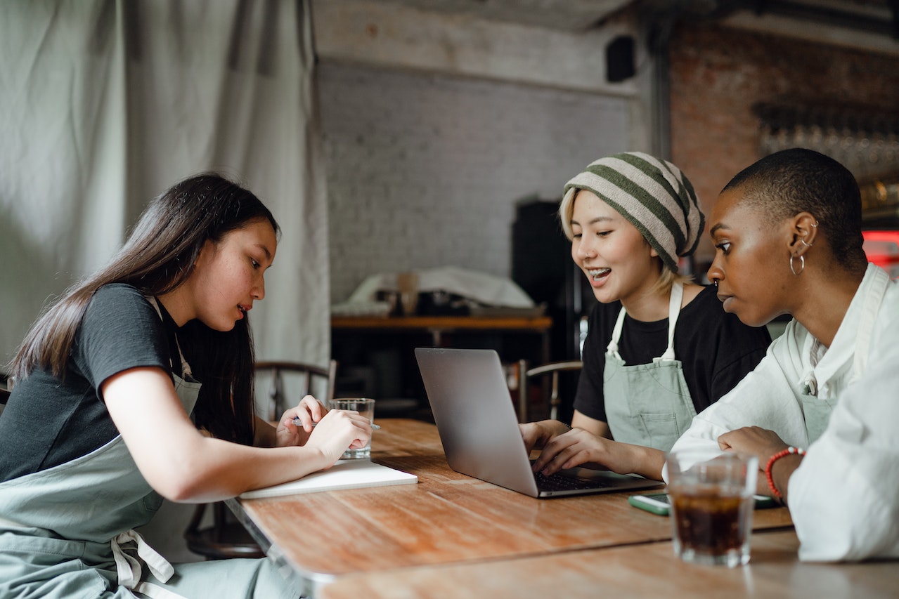 three diverse women discussing business around a laptop