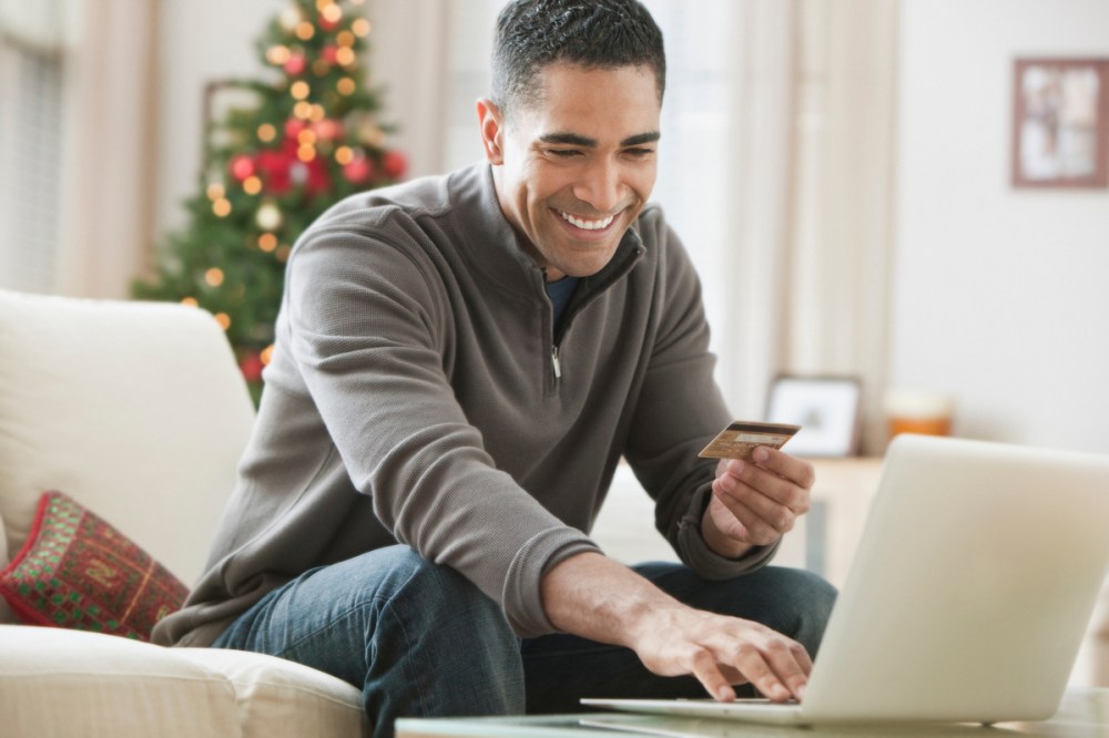 Mixed race man holding credit card and using laptop