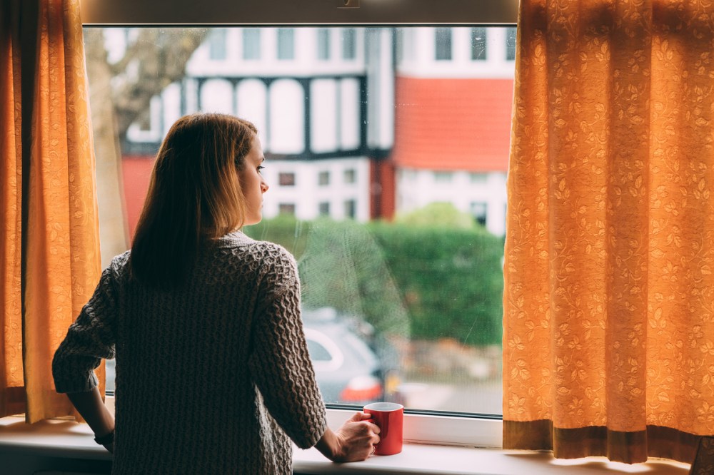 Polish woman looking out the window of her home.