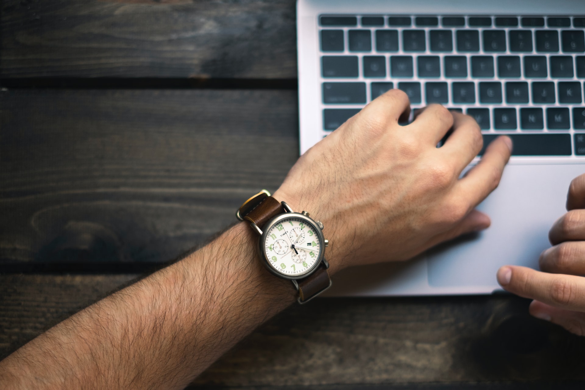 A man’s wristwatch beside a laptop, indicating a product launch on time