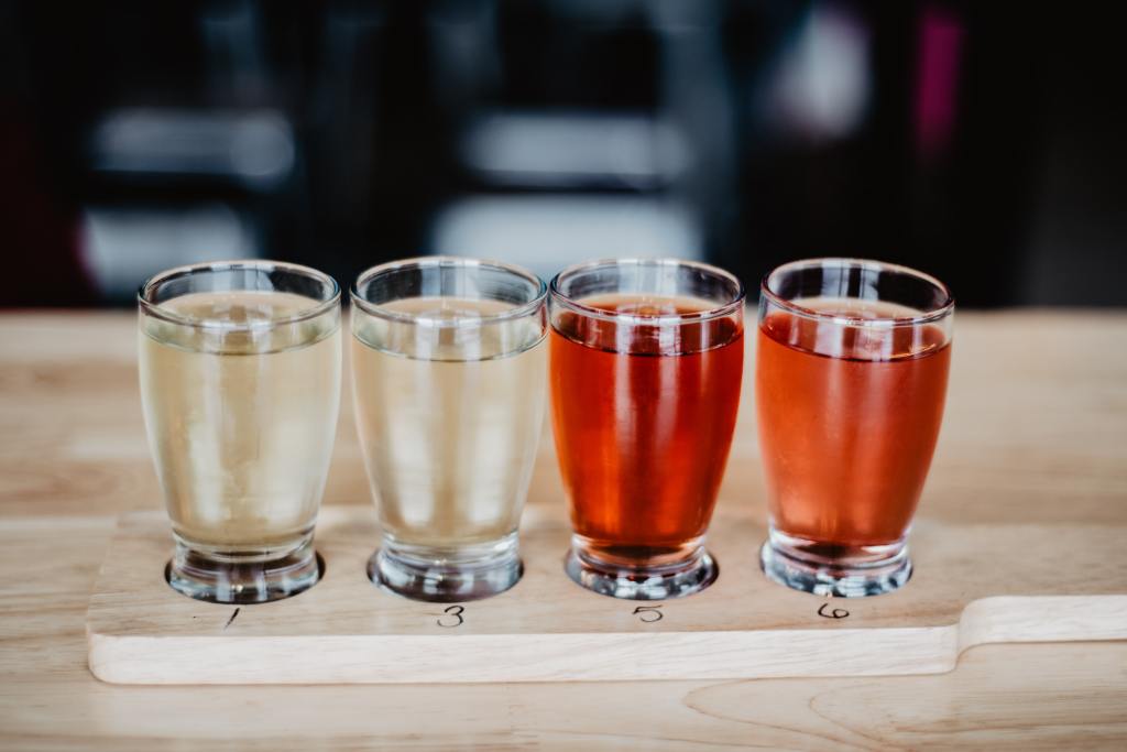 Four glasses of hard cider on a bar