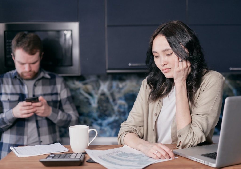 A worried couple makes a budget at a coffee table to respond to rising interest rates.