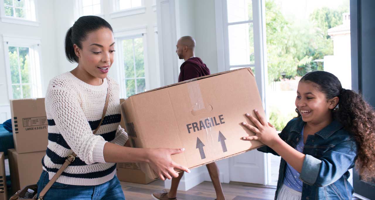 Woman and child holding a cardboard box labeled Fragile