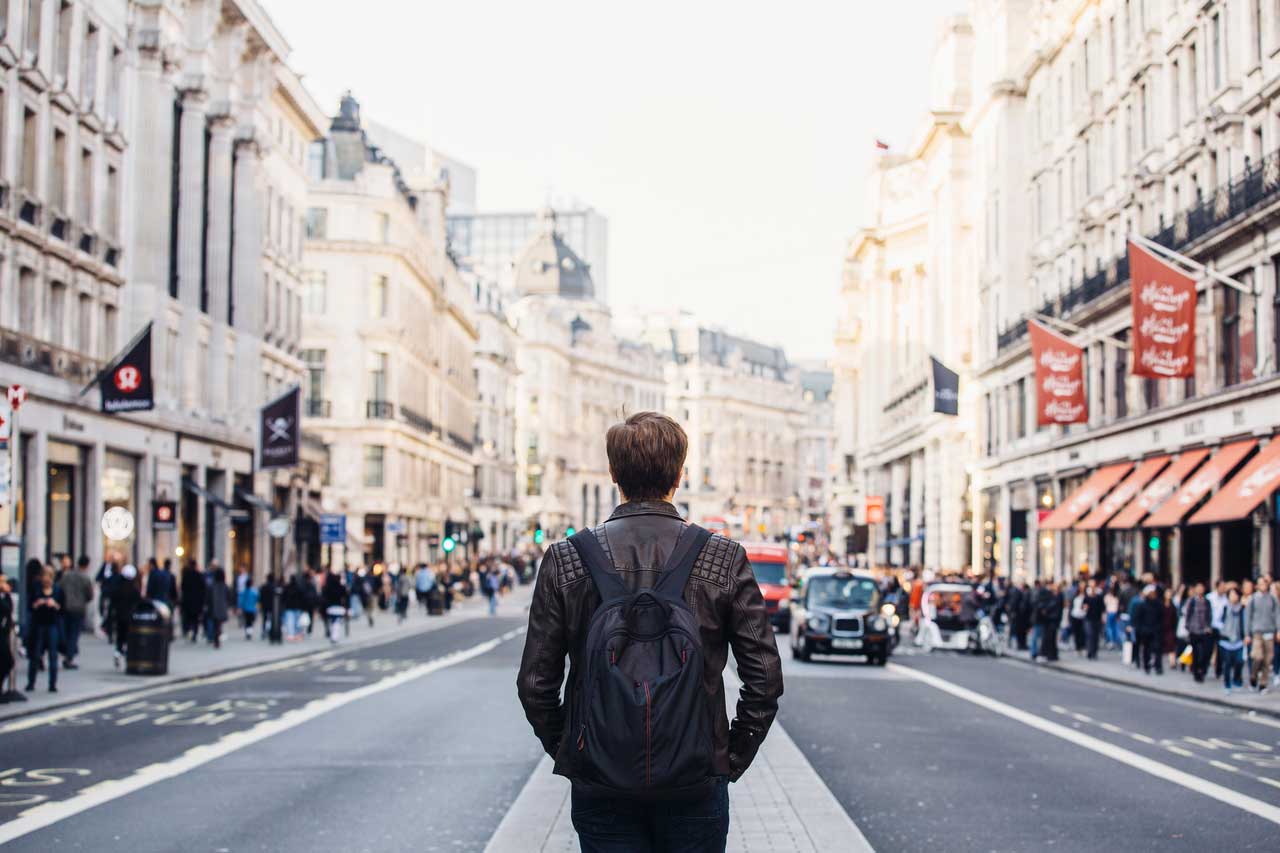 Man on European street with a leather coat and backpack