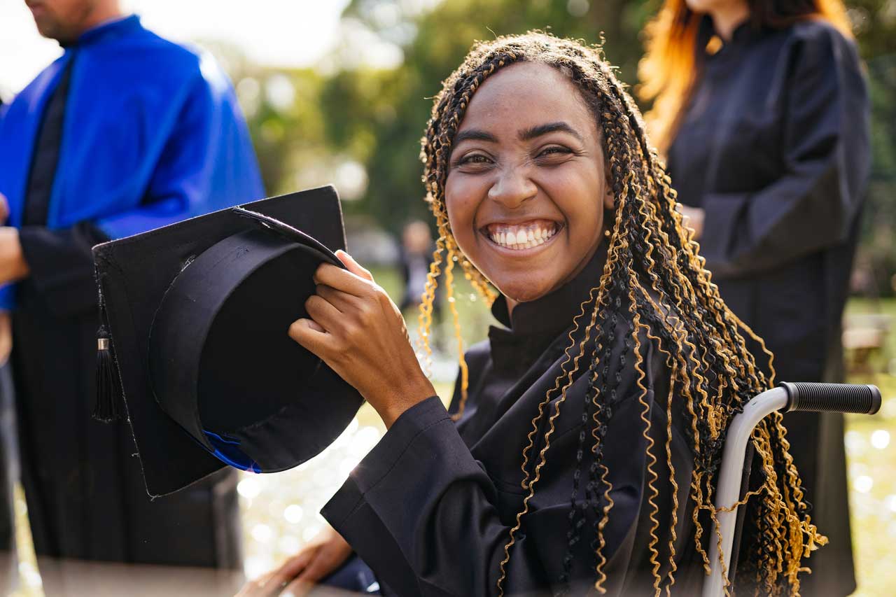 Woman smiling holding her graduation cap