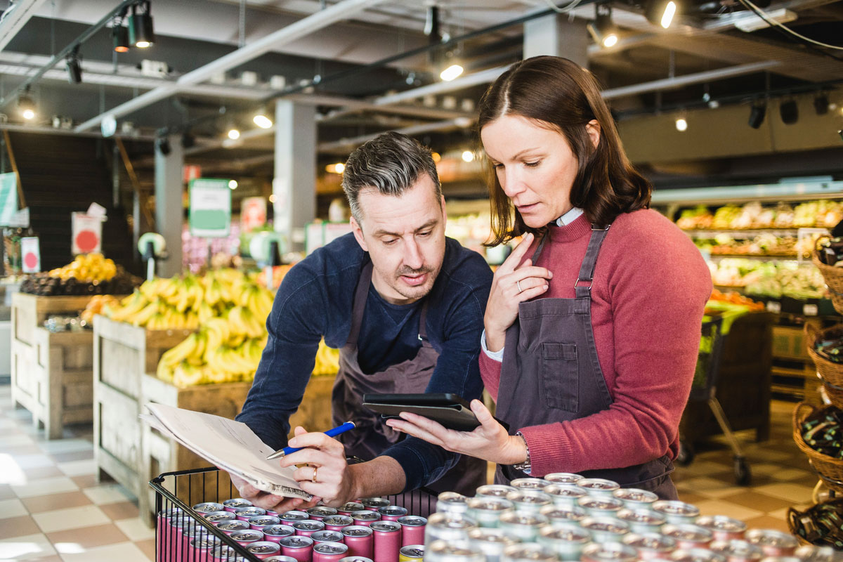 Store owners discussing over digital tablet by drink cans