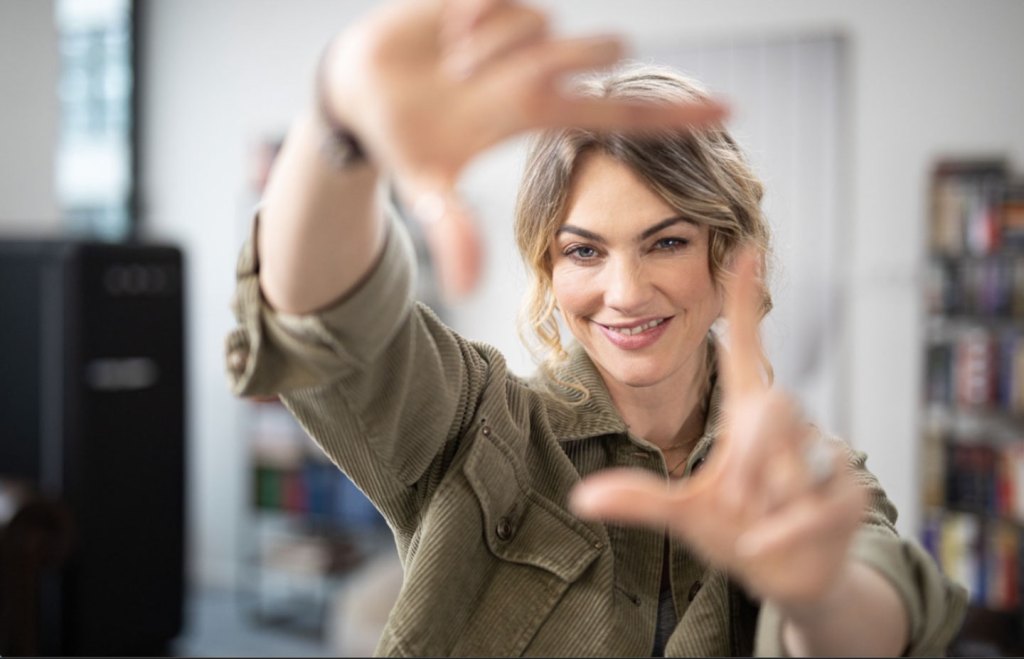 Woman holding her hands up to the camera framing her face in the picture