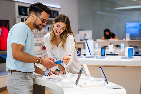 Shopping a new digital device. Happy couple buying a mobile phone in store.