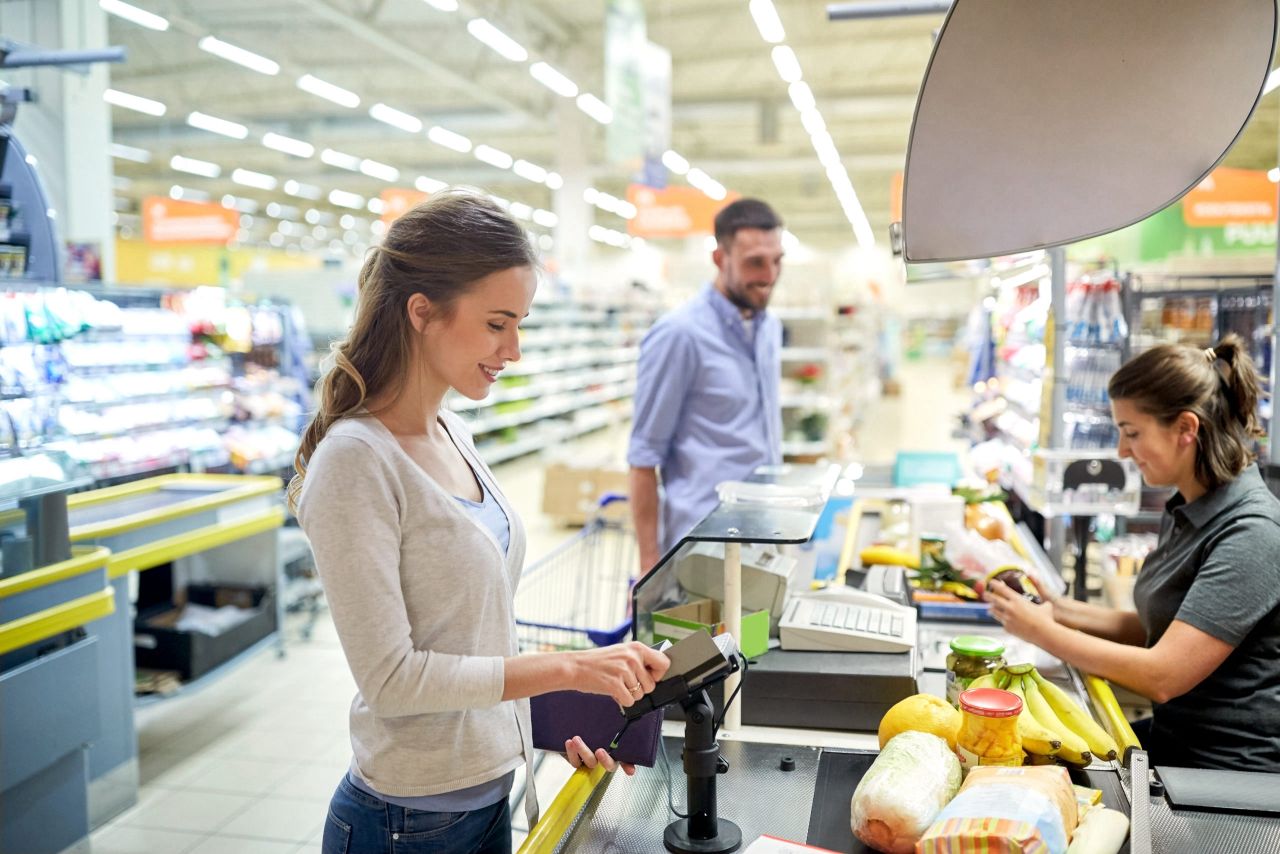 Grocery shopper swiping loyalty card at checkout register