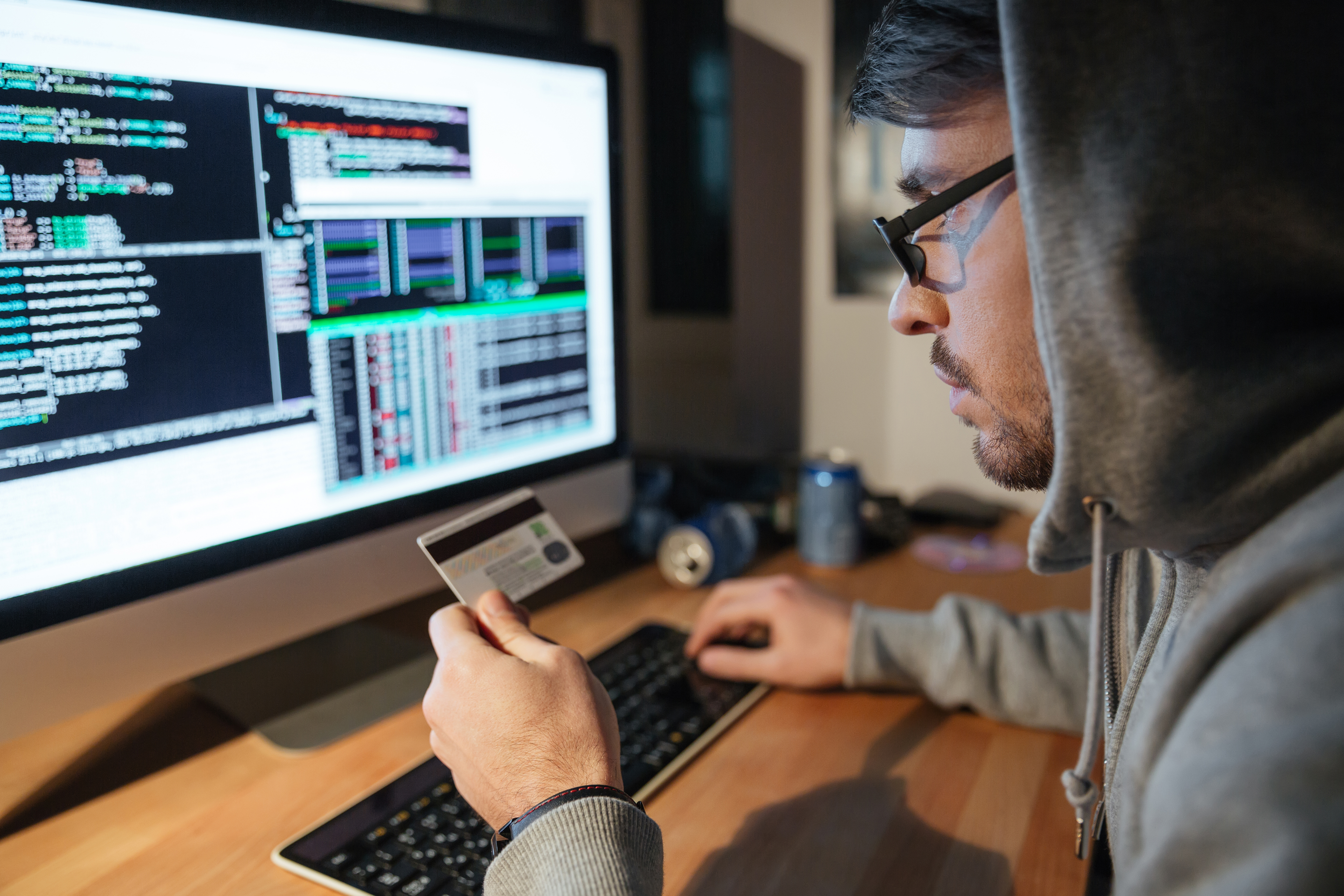 Young man in glasses ponders whether to make a transaction with his credit card online