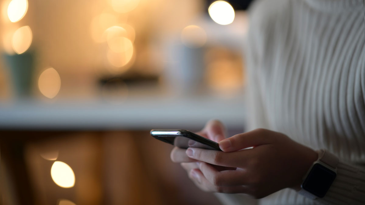 Woman in white sweater using a cell phone