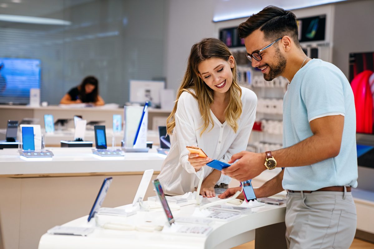 Shopping a new digital device. Happy couple buying a smartphone in store.
