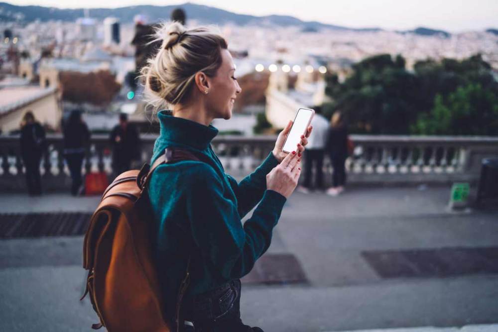 A traveler with a backpack looking at her phone while walking