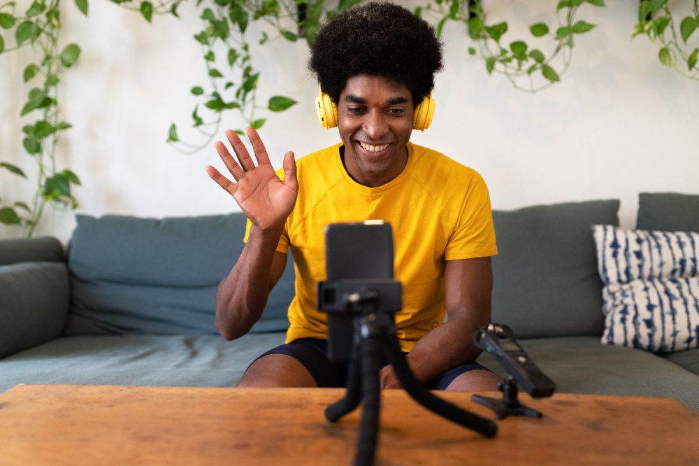 Young african american influencer waving hello to followers. Recording himself for video tutorial with mobile phone