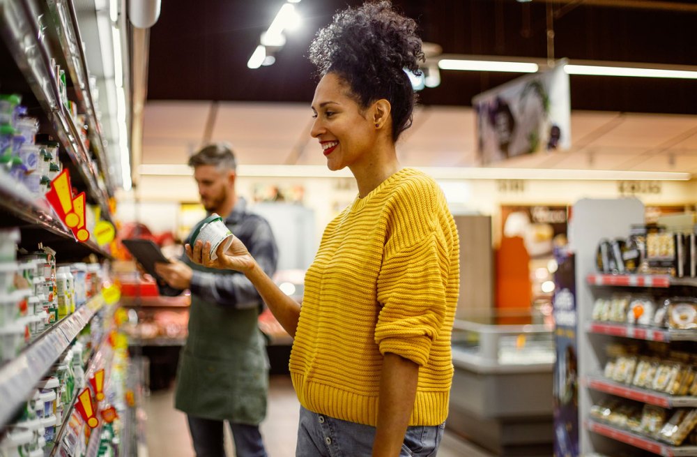 Woman with yellow shirt holds a product in a grocery store