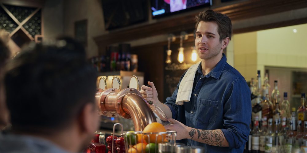 male bartender serving beer at bar