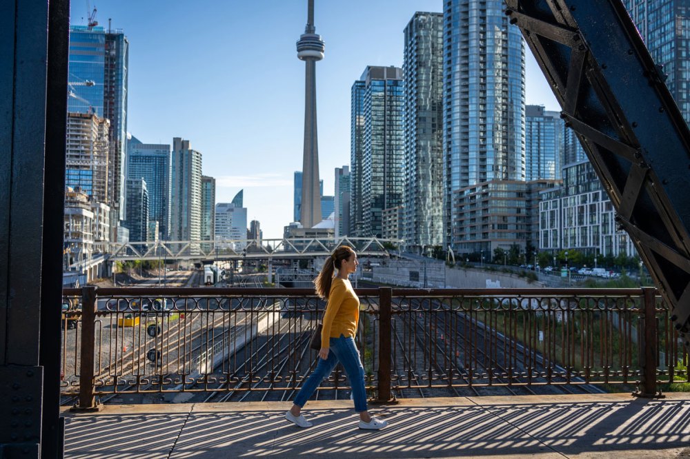 A woman in a yellow shirt with a ponytail walking across a bridge somehwere in Canada