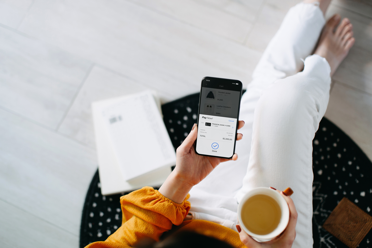 Overhead view of young Asian woman relaxing at home, shopping online with smartphone and making payment online with credit card. Lifestyle and technology. Contactless payment. Comfortable and fast shopping experience