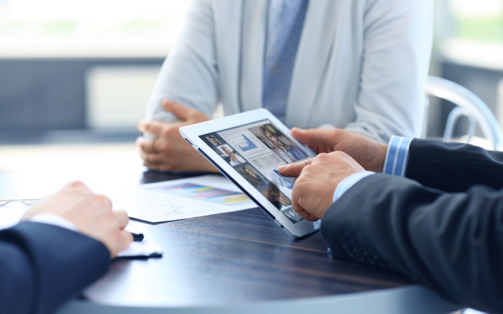 Close up of person video conferencing with colleagues on digital tablet, analyzing financial statistics displayed on the digital tablet screen