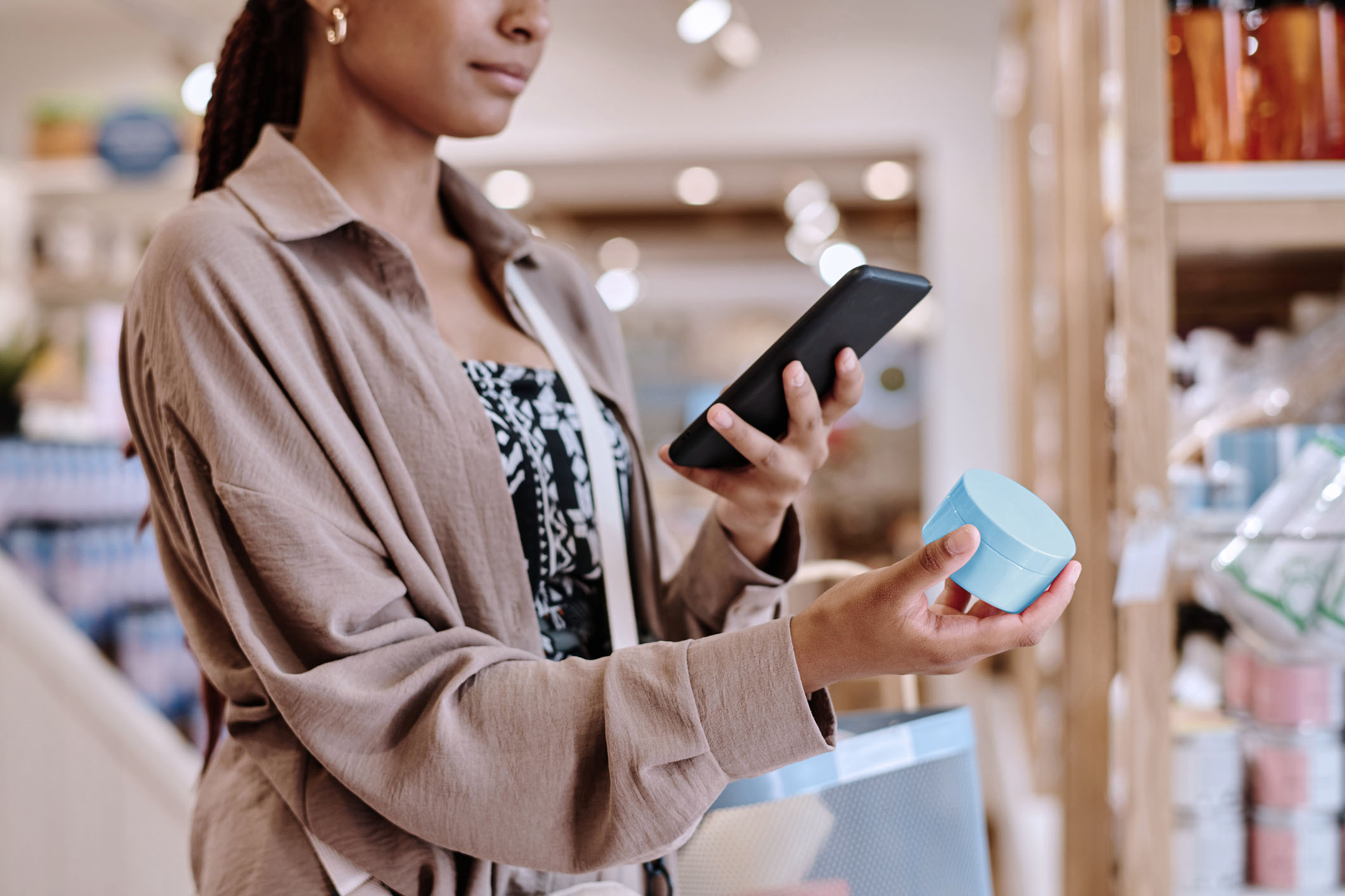 Chapter 5 of the Consumer outlook 2026​ report shows a shopper looking at cosmetics in a store and shopping on her phone as well