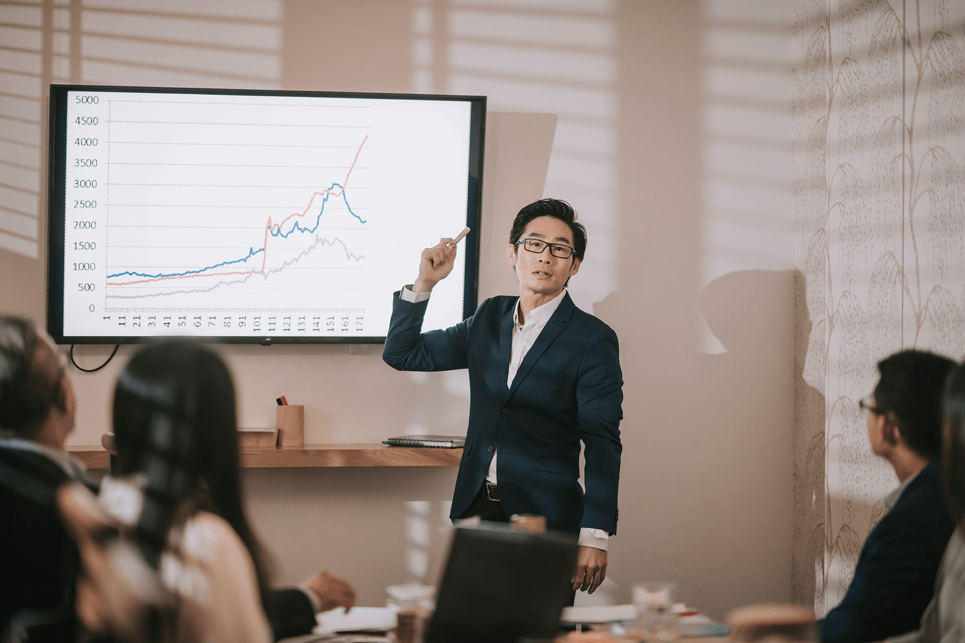 Man giving lecture in front of monitor showing a graph